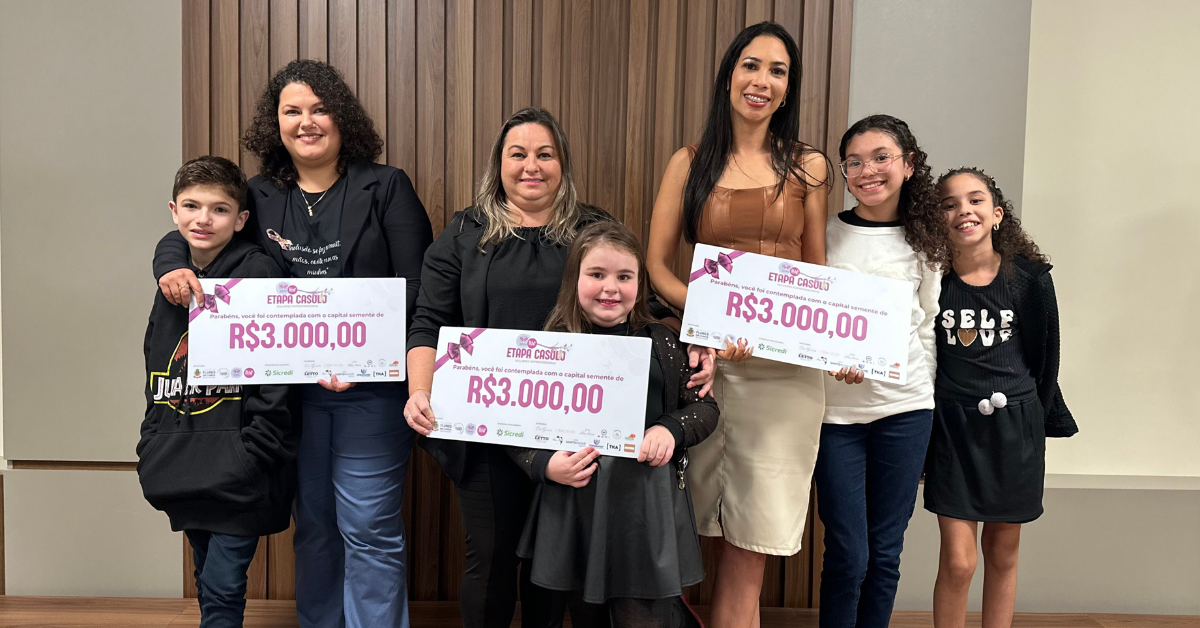 Mulheres exibindo cheques simbólicos do programa