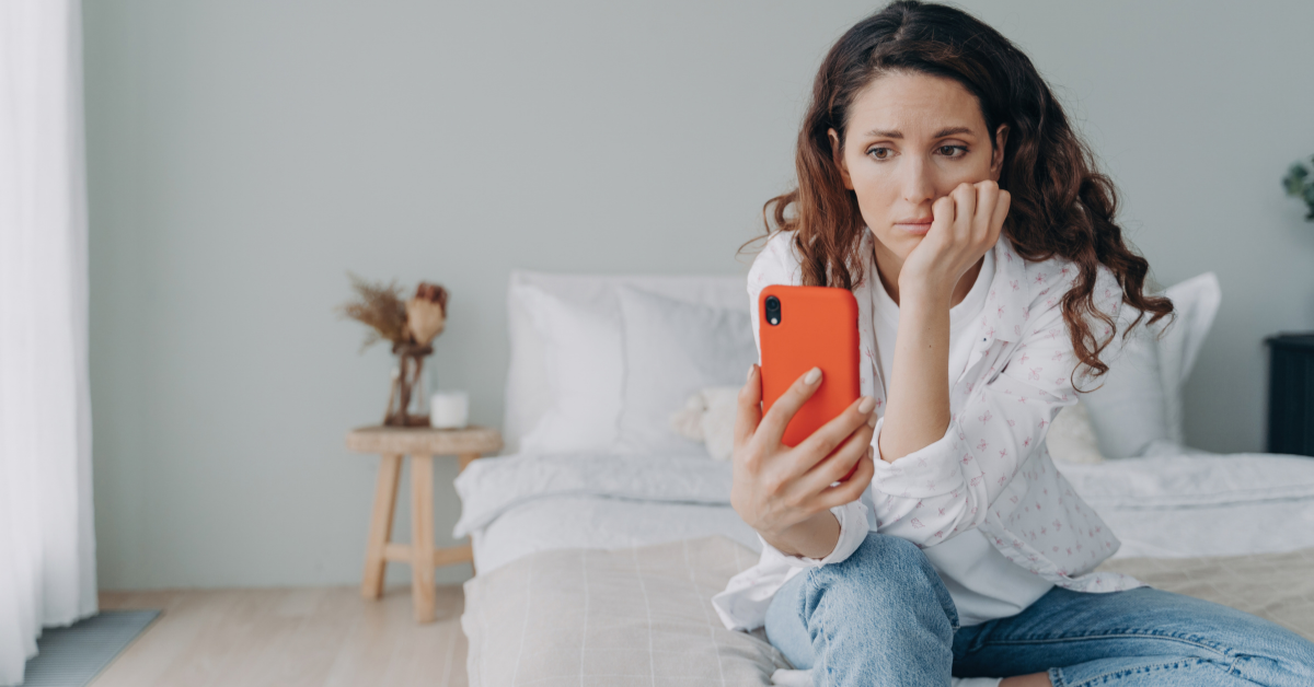 Mulher apreensiva segurando um celular