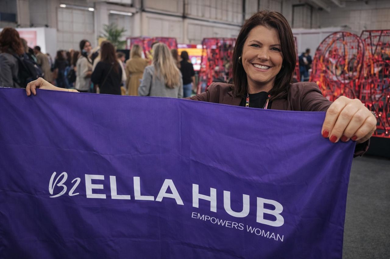 Paty Janczak segurando a bandeira do Ella Hub em um evento de inovação